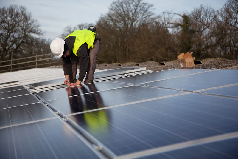 man op dak legt zonnepanelen